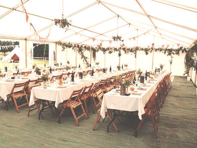 Beautiful wedding dining setup with round tables, white linens, floral centerpieces, and luxury tent designed by On Board Catering for a wedding in Raleigh.
